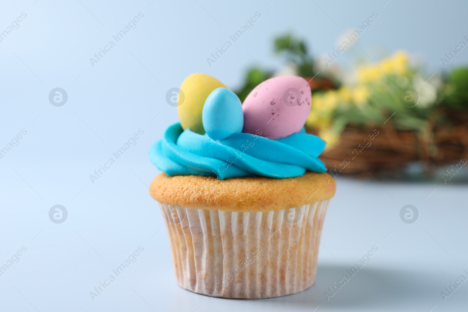 Photo of Tasty decorated Easter cupcake on light blue background, closeup