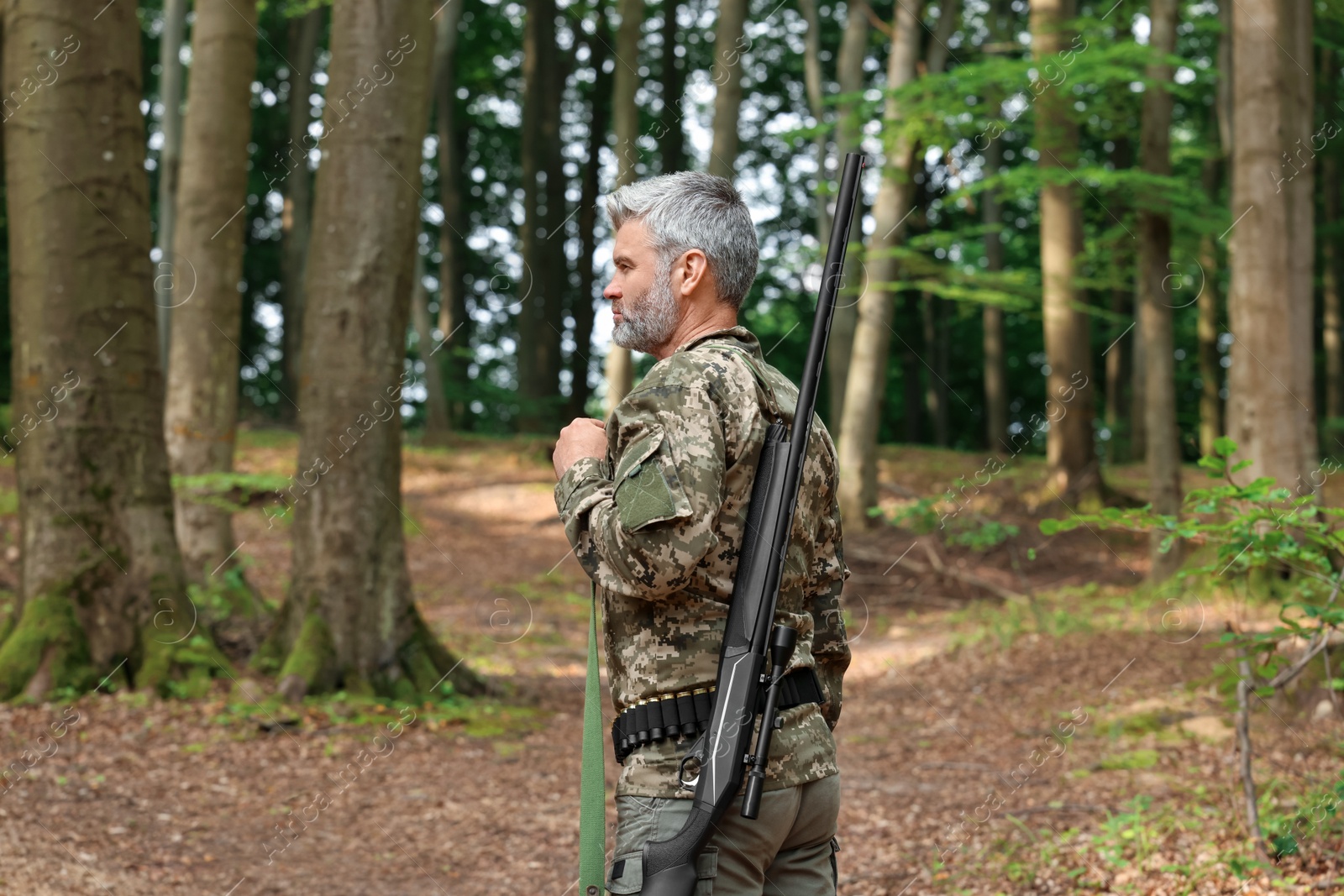 Photo of Man with hunting rifle wearing camouflage in forest