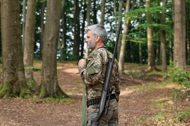 Photo of Man with hunting rifle wearing camouflage in forest