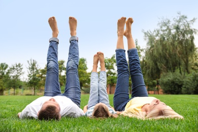 Photo of Happy family lying on green grass in park