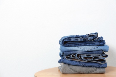 Photo of Stack of different jeans on table against white background. Space for text