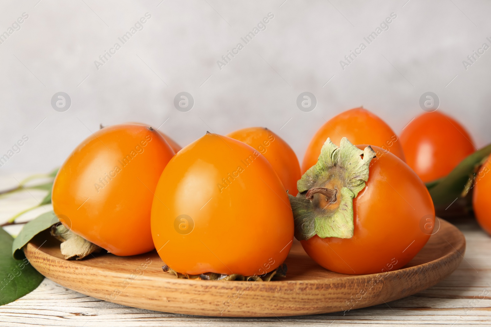 Photo of Delicious fresh persimmons on white wooden table, closeup