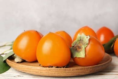 Photo of Delicious fresh persimmons on white wooden table, closeup