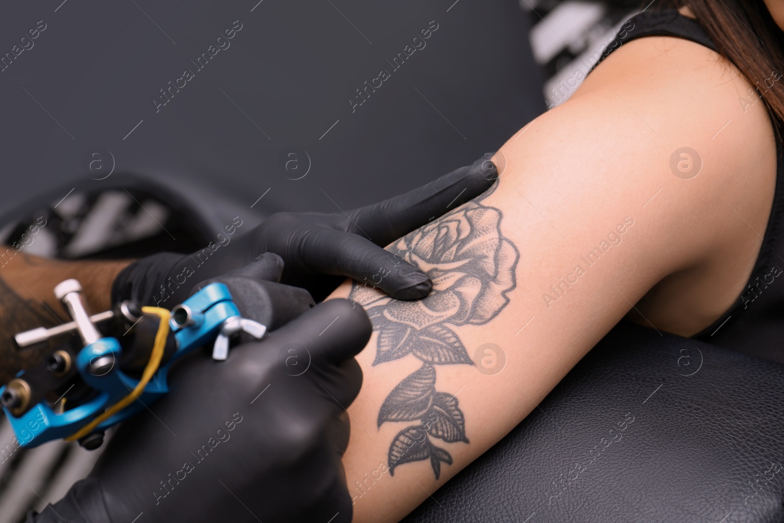 Photo of Professional artist making tattoo in salon, closeup