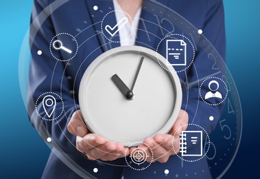 Image of Time management concept. Woman holding clock surrounded by icons, closeup