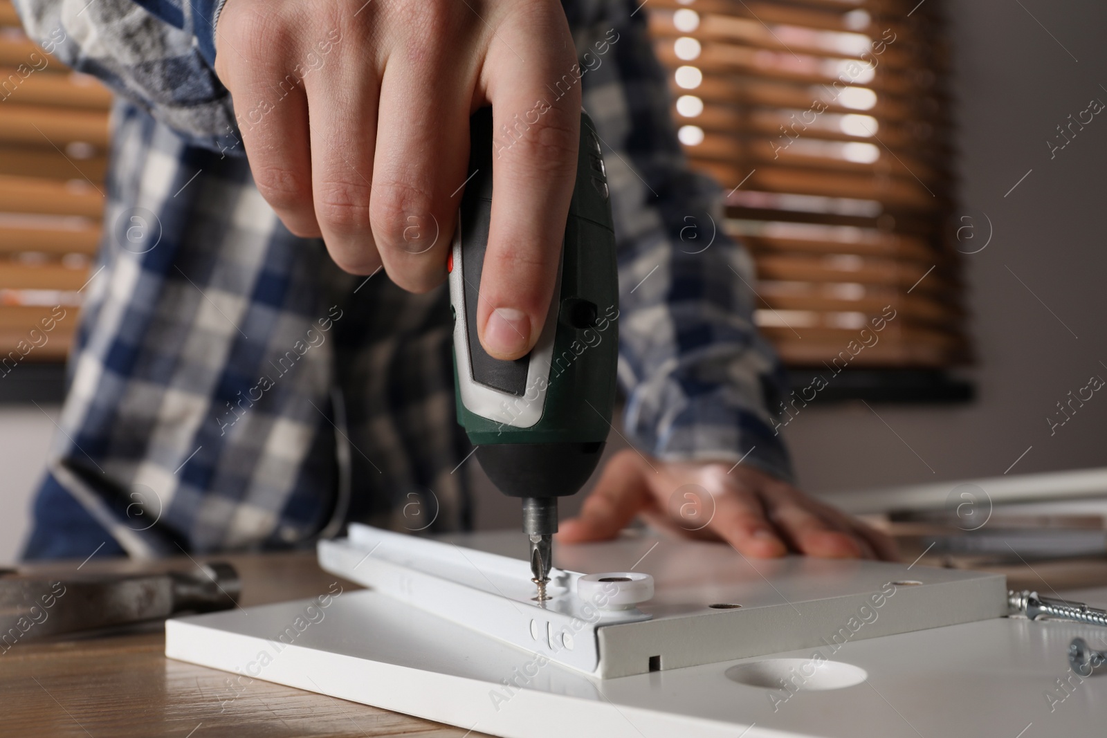 Photo of Man assembling furniture at table indoors, closeup