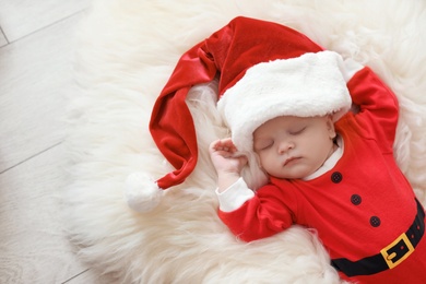 Photo of Cute baby in Christmas costume sleeping on fur rug