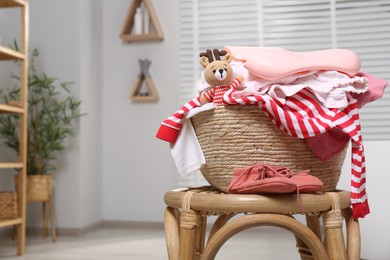 Photo of Laundry basket with baby clothes and crochet toy indoors, space for text