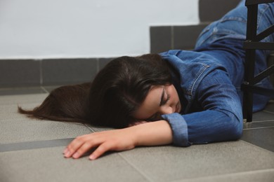 Photo of Unconscious woman lying on floor after falling down stairs indoors