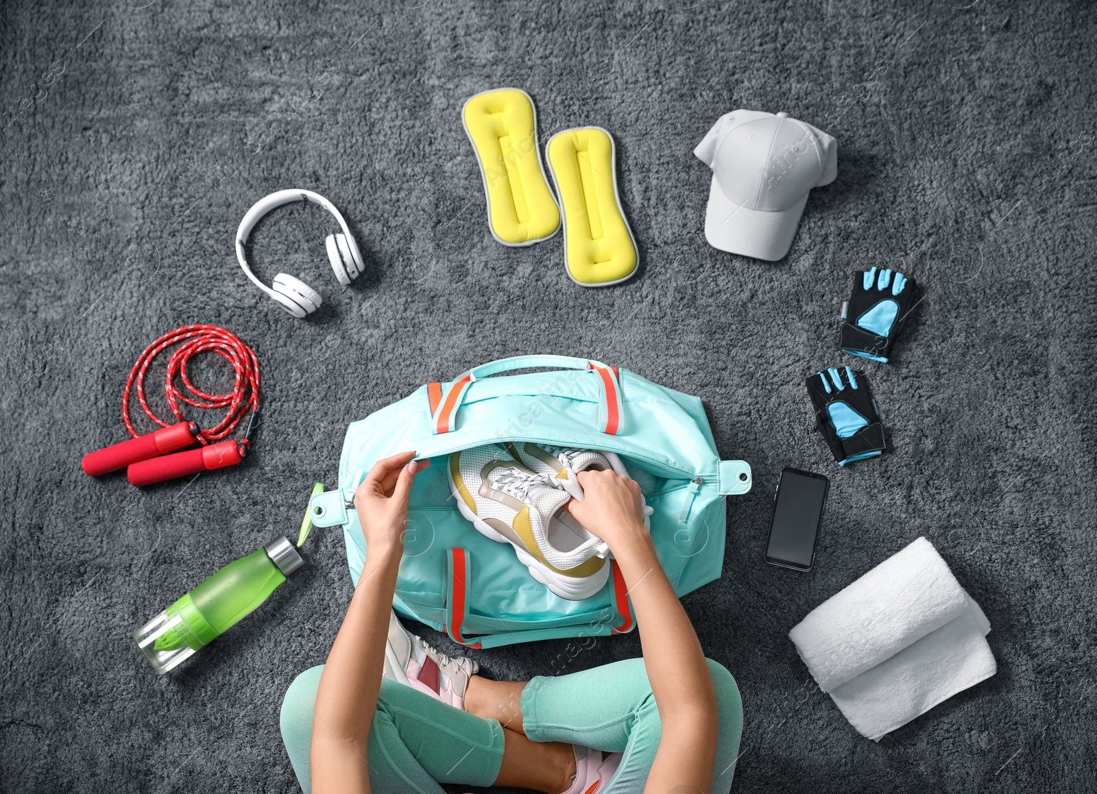 Photo of Woman with bag and sports items on grey carpet, top view