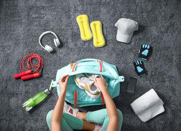 Woman with bag and sports items on grey carpet, top view