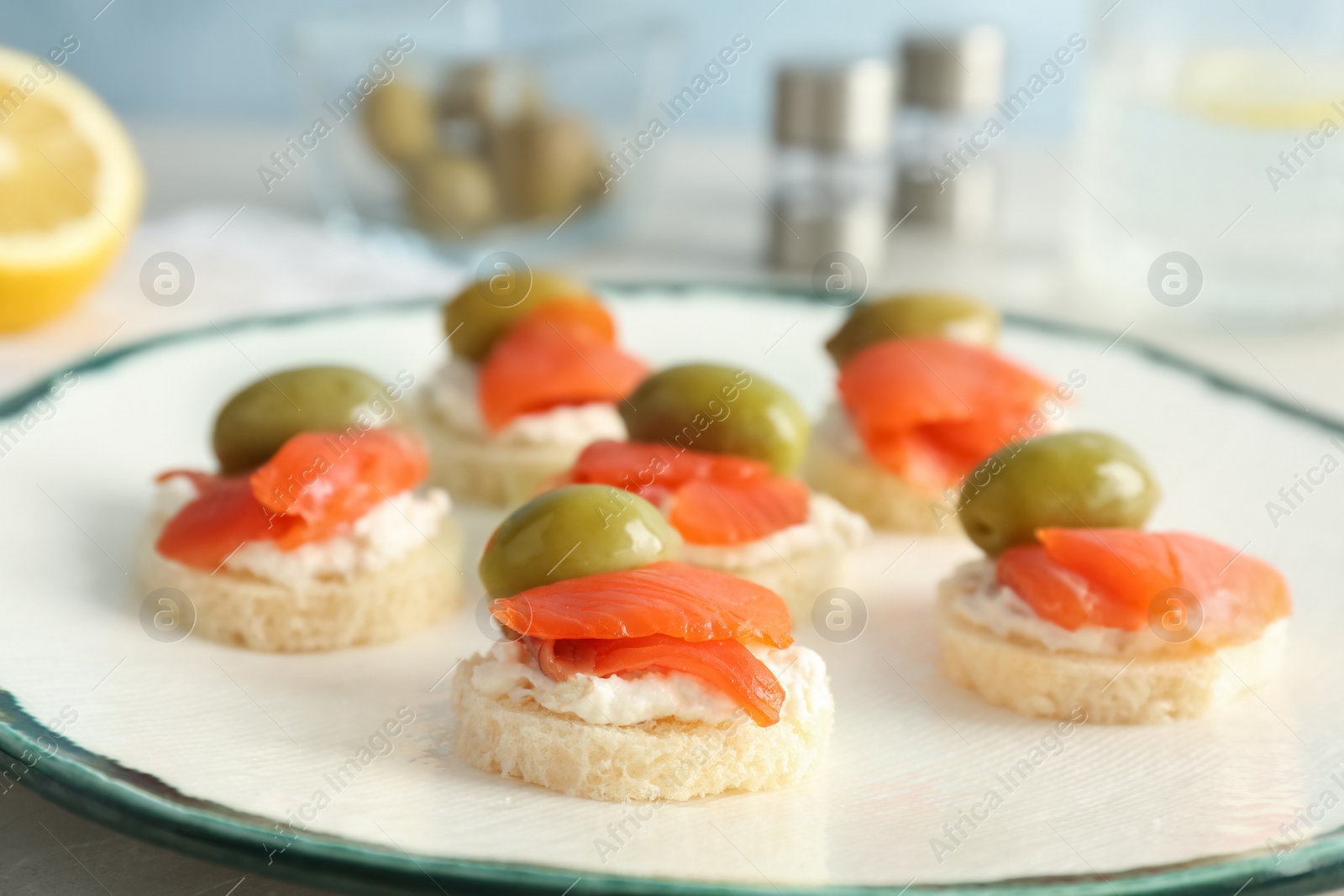 Photo of Tasty sandwiches with fresh sliced salmon fillet and olives on plate, closeup