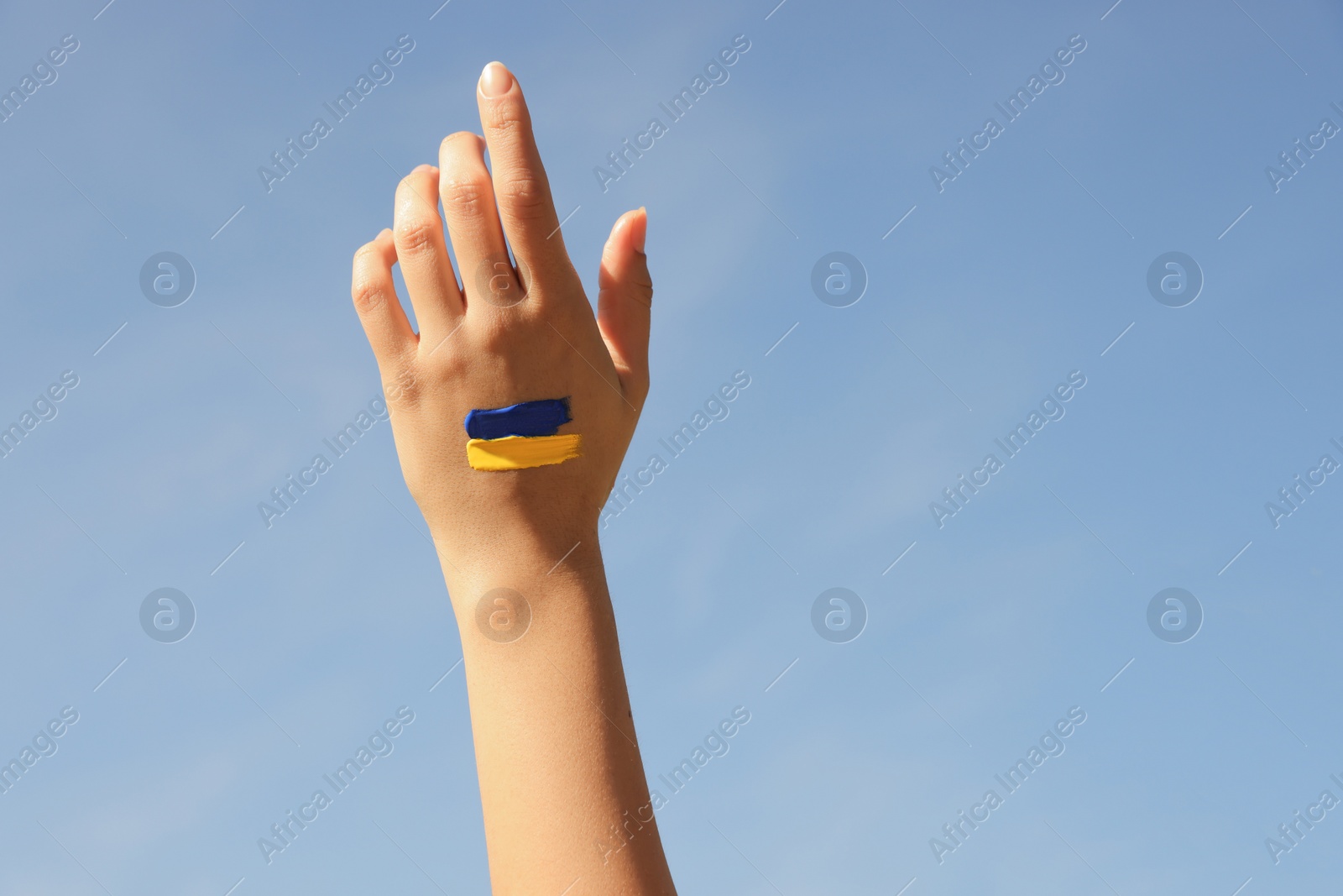 Photo of Woman with drawing of Ukrainian flag on hand outdoors, closeup. Space for text