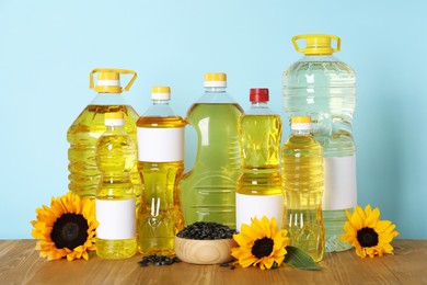 Bottles of cooking oil, sunflowers and seeds on wooden table