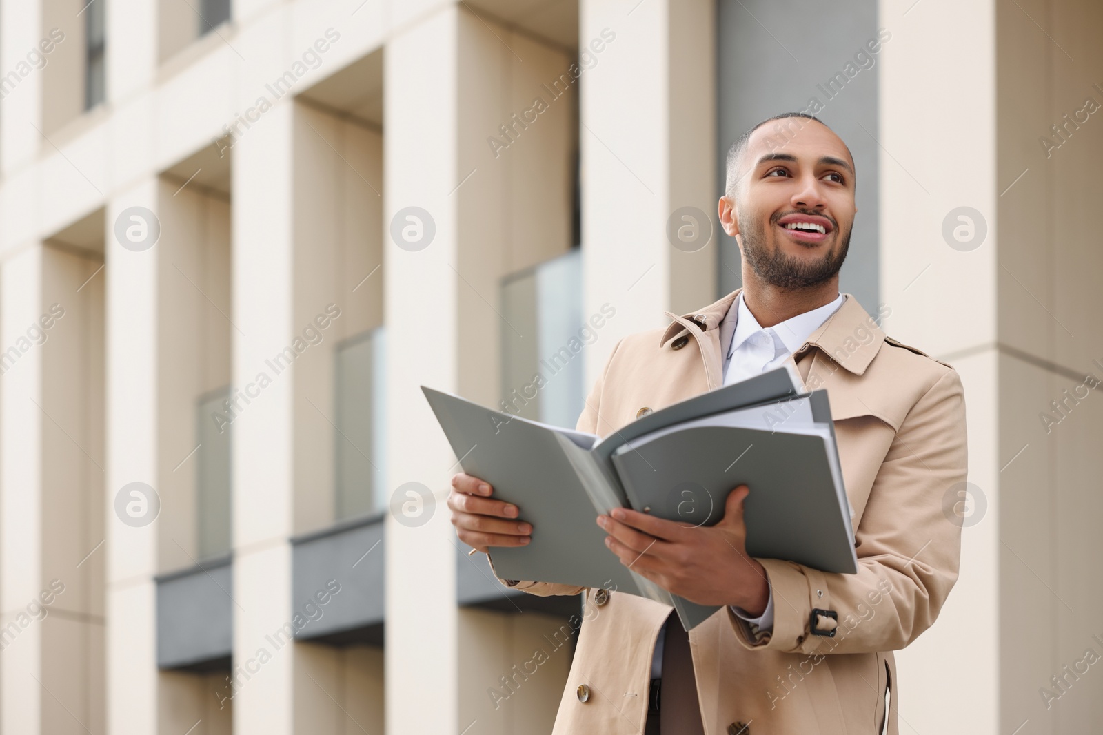 Photo of Happy man with folders outdoors, space for text. Lawyer, businessman, accountant or manager
