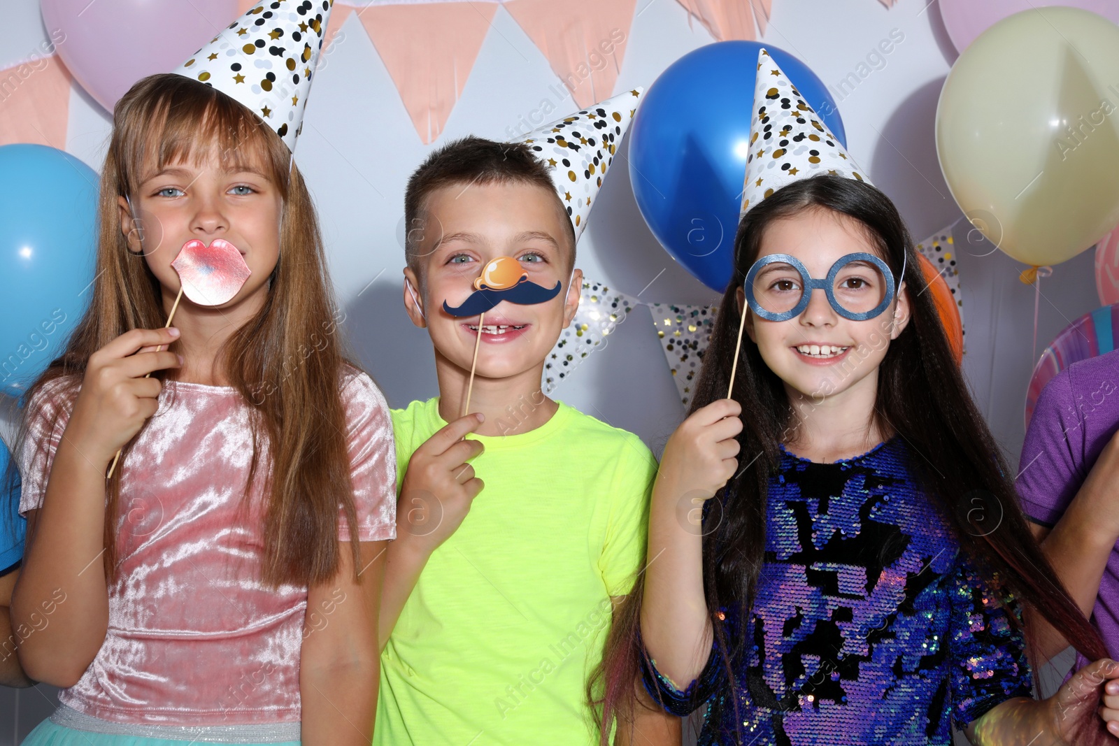 Photo of Happy children with photo booth props at birthday party indoors