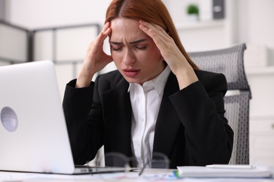 Woman suffering from headache at workplace in office