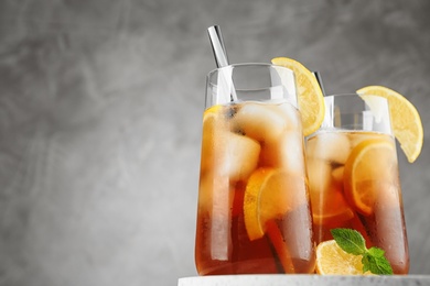 Photo of Glasses of refreshing iced tea against grey background. Space for text