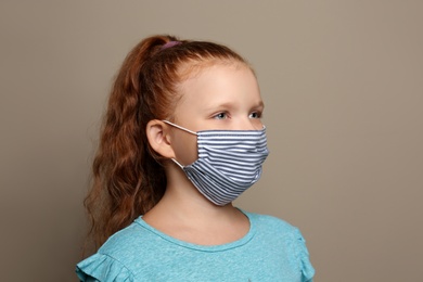 Photo of Preteen girl in protective face mask on brown background