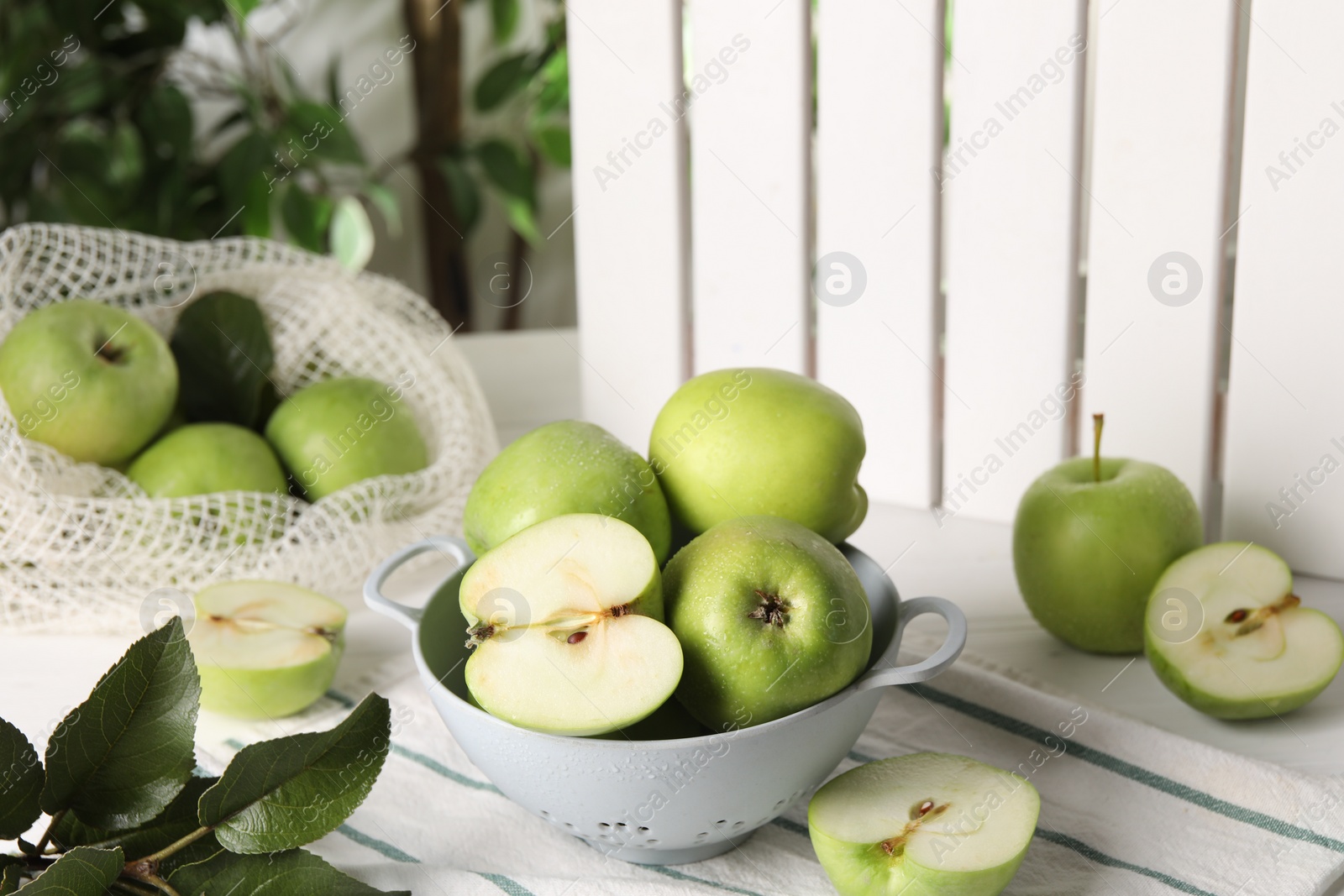 Photo of Fresh green apples with water drops and leaves on white table