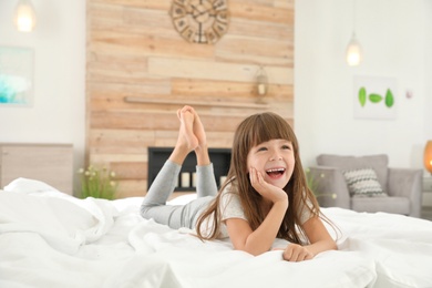 Photo of Cute little girl lying on bed at home