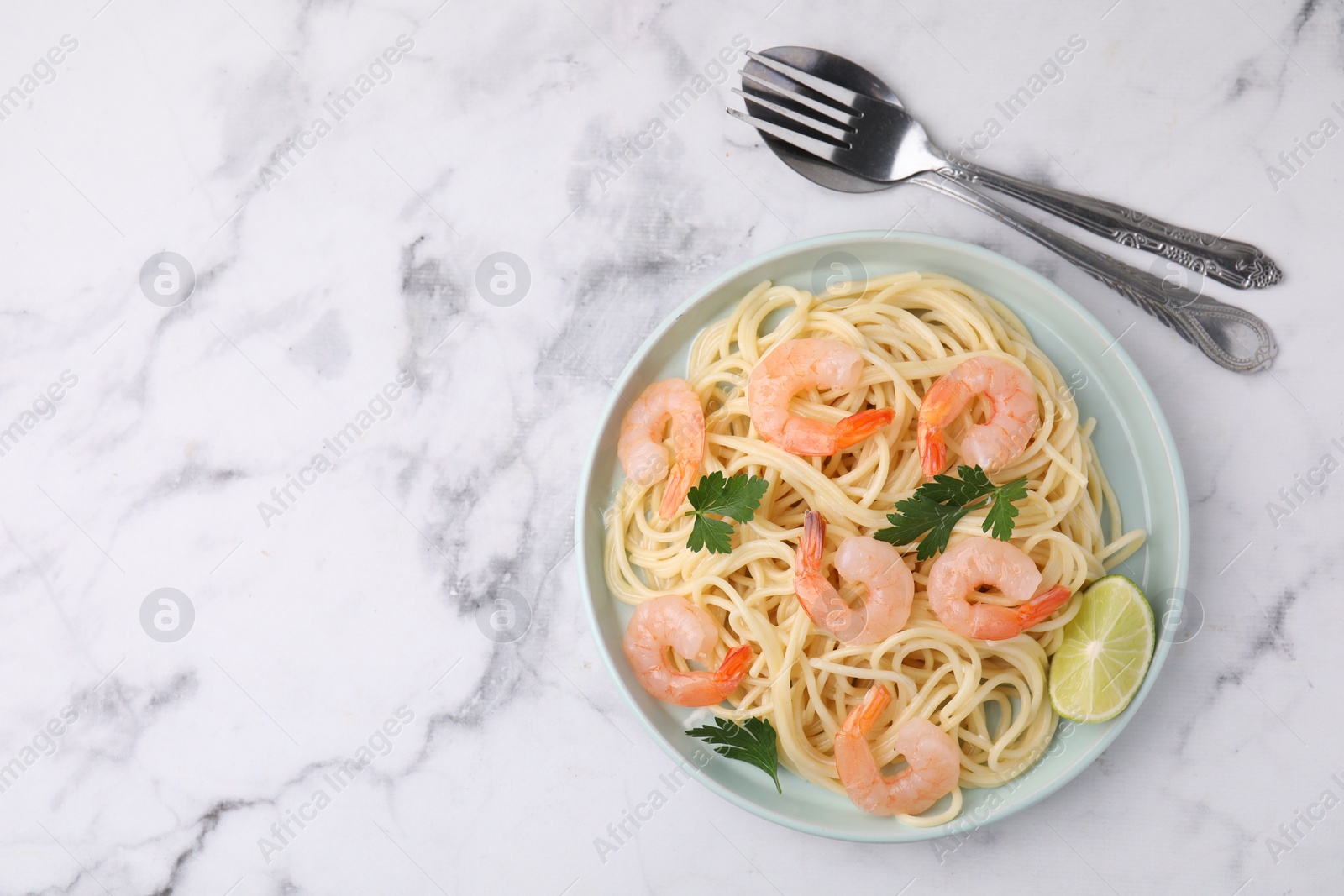 Photo of Tasty spaghetti with shrimps, lime and parsley served on white marble table, top view. Space for text