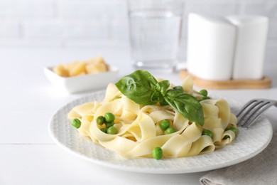 Photo of Delicious pasta with green peas served on white table