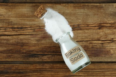 Photo of Overturned jar with baking soda on wooden table, top view