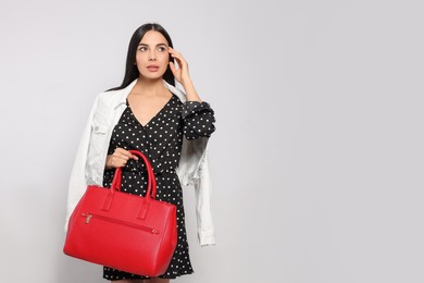 Young woman with stylish bag on white background,