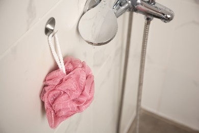 Pink shower puff hanging near faucet in bathroom