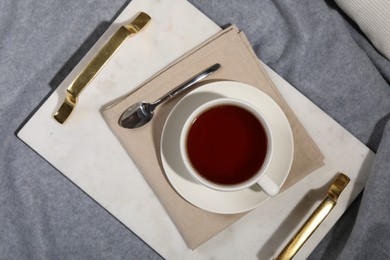 Photo of Aromatic tea in cup, saucer and spoon on table, top view