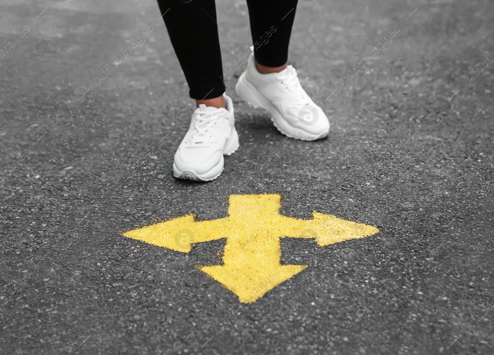 Photo of Woman standing near arrow on asphalt, closeup