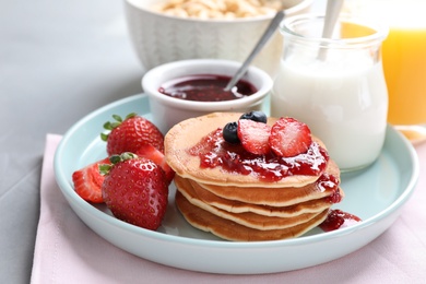 Fresh pancakes with jam and strawberries on light grey table. Healthy breakfast