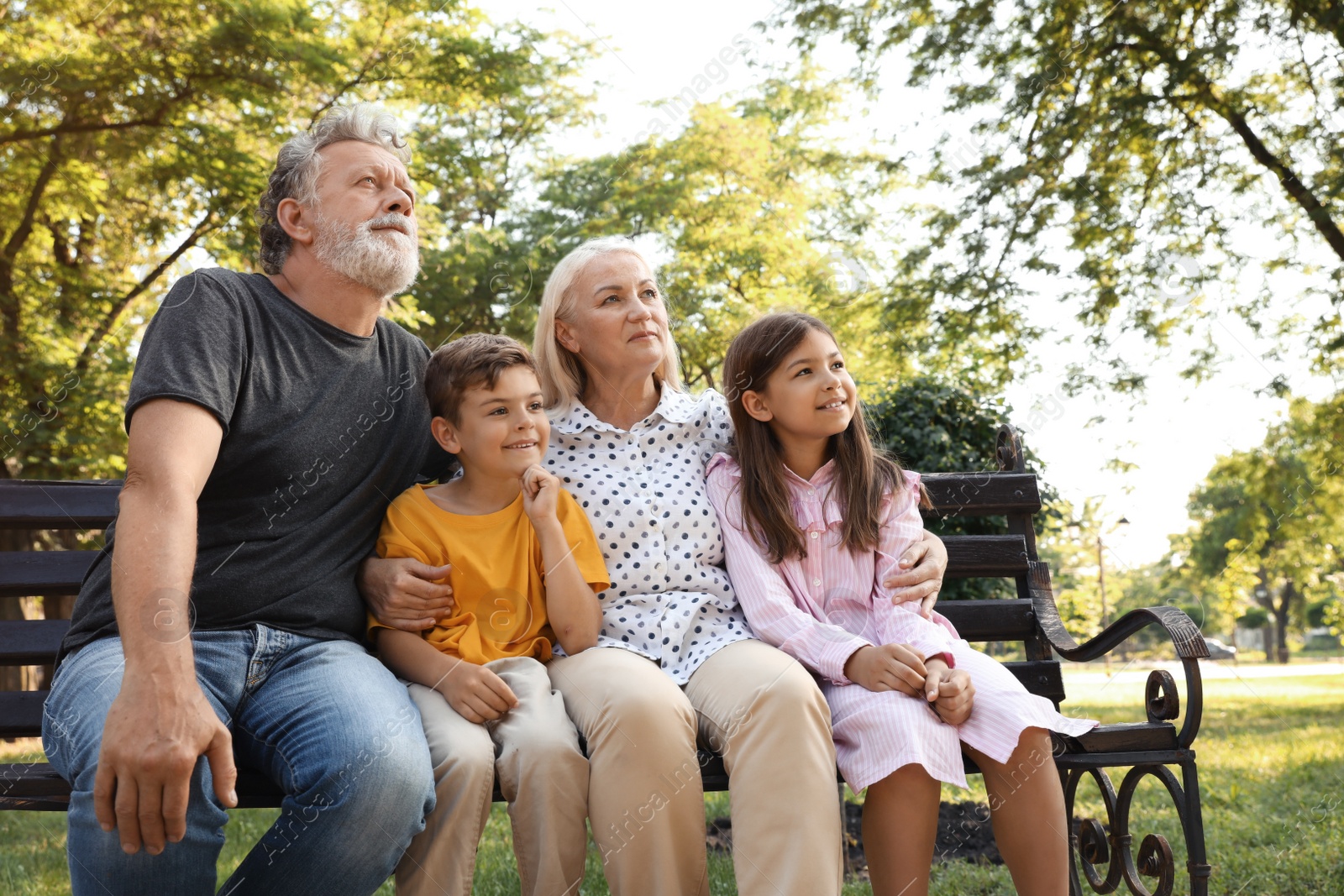 Photo of Happy grandparents with little children resting together in park