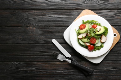 Photo of Delicious fresh chicken salad served on black wooden table, flat lay. Space for text