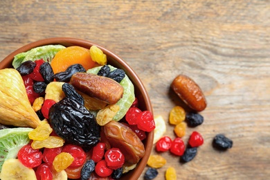 Photo of Bowl of different dried fruits on wooden background, top view with space for text. Healthy lifestyle
