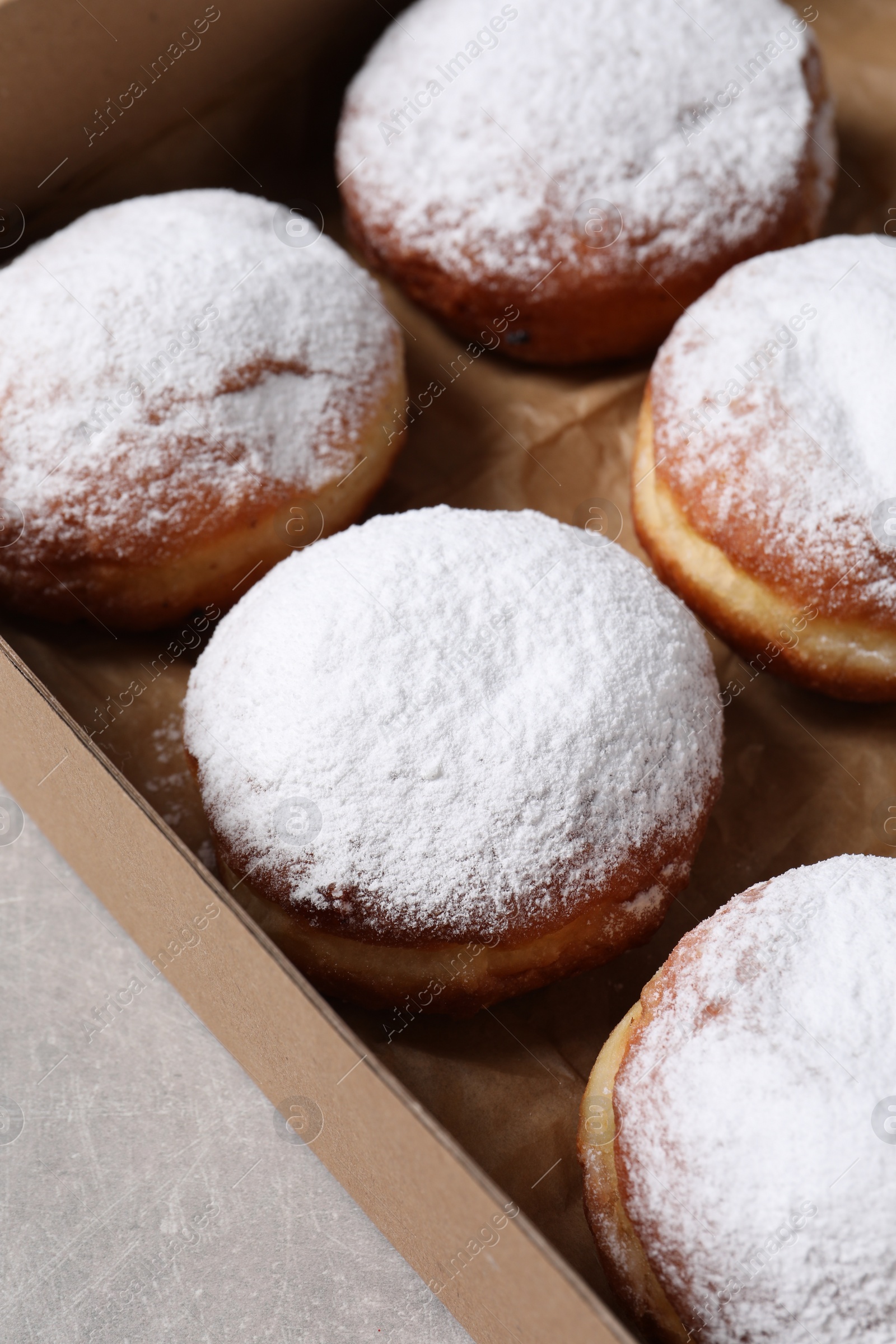 Photo of Delicious buns with powdered sugar on light grey table, closeup