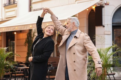 Affectionate senior couple dancing together on city street