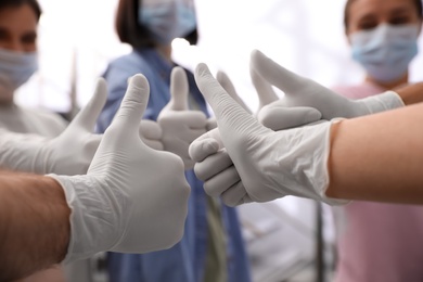 Photo of Group of people in white medical gloves showing thumbs up on blurred background, closeup