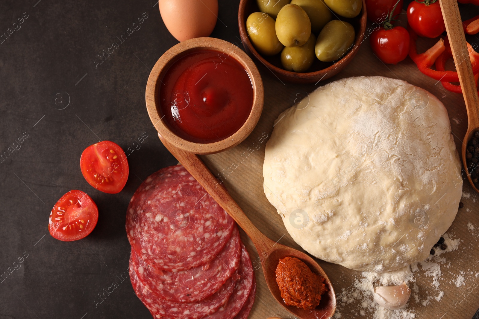 Photo of Pizza dough and products on dark table, flat lay