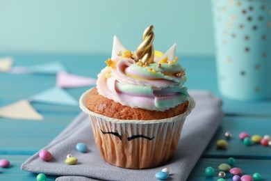 Cute sweet unicorn cupcake on light blue wooden table