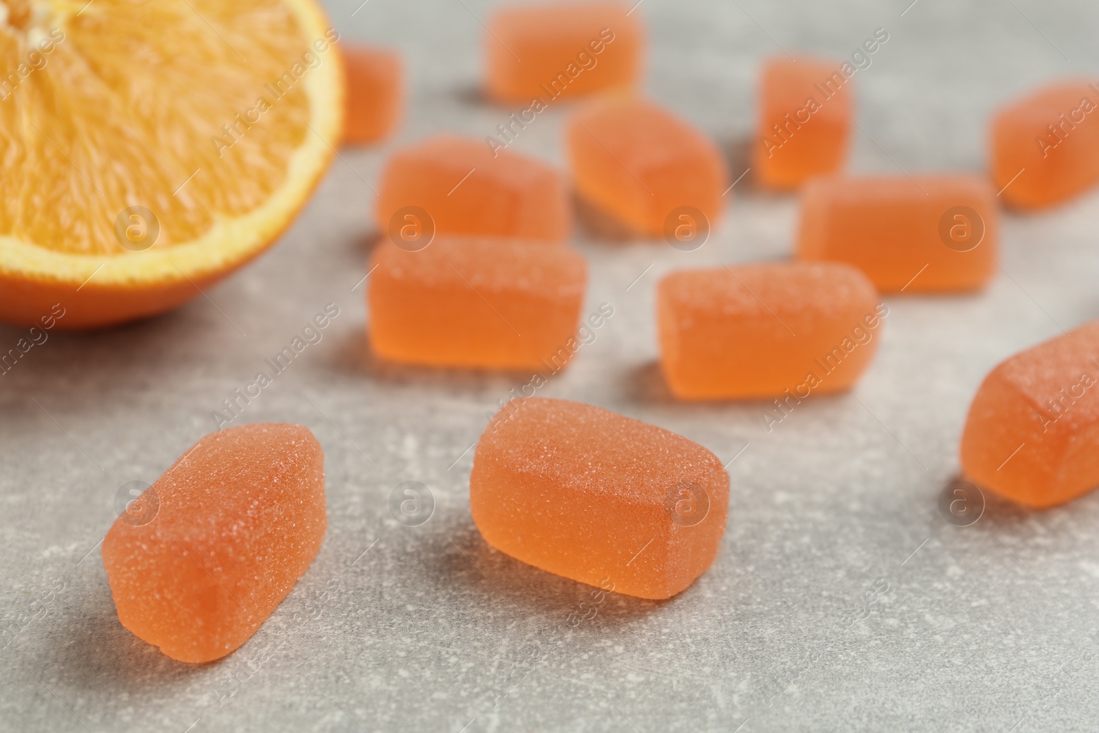 Photo of Tasty orange jelly candies on grey table, closeup