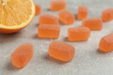 Tasty orange jelly candies on grey table, closeup