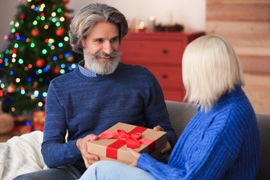 Happy couple opening Christmas gift at home