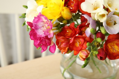 Beautiful spring bright freesia flowers in vase on table, closeup