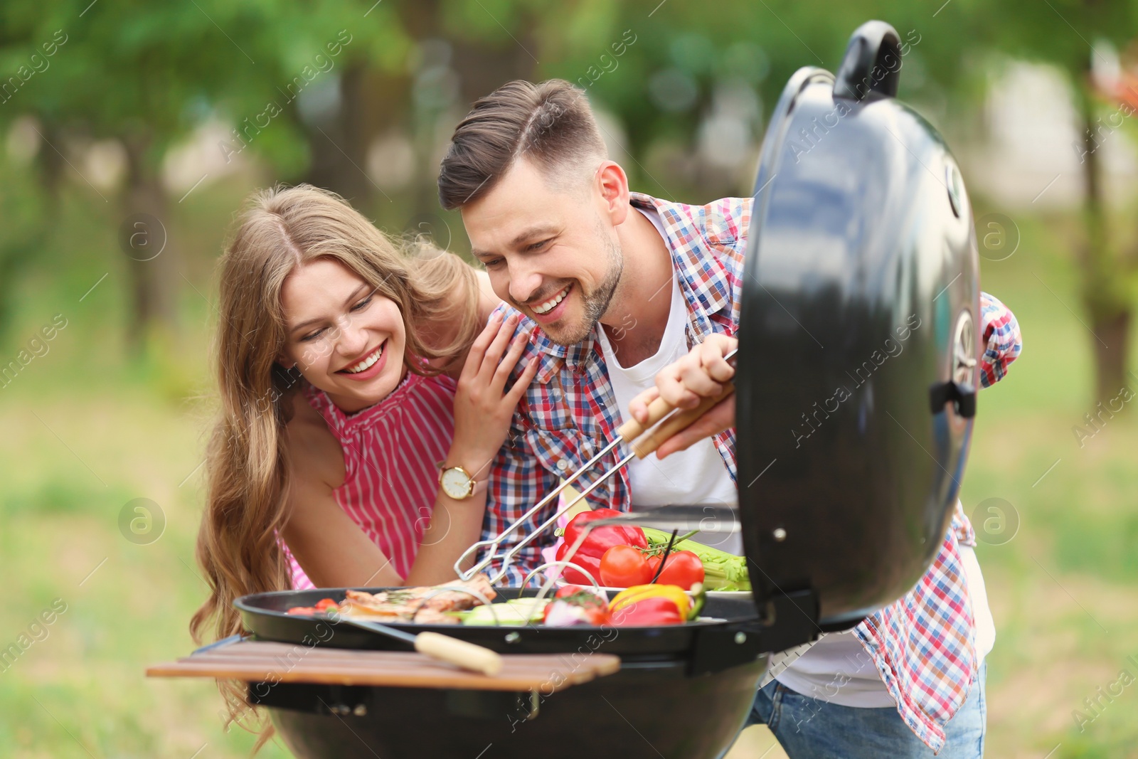 Photo of Young people having barbecue with modern grill outdoors