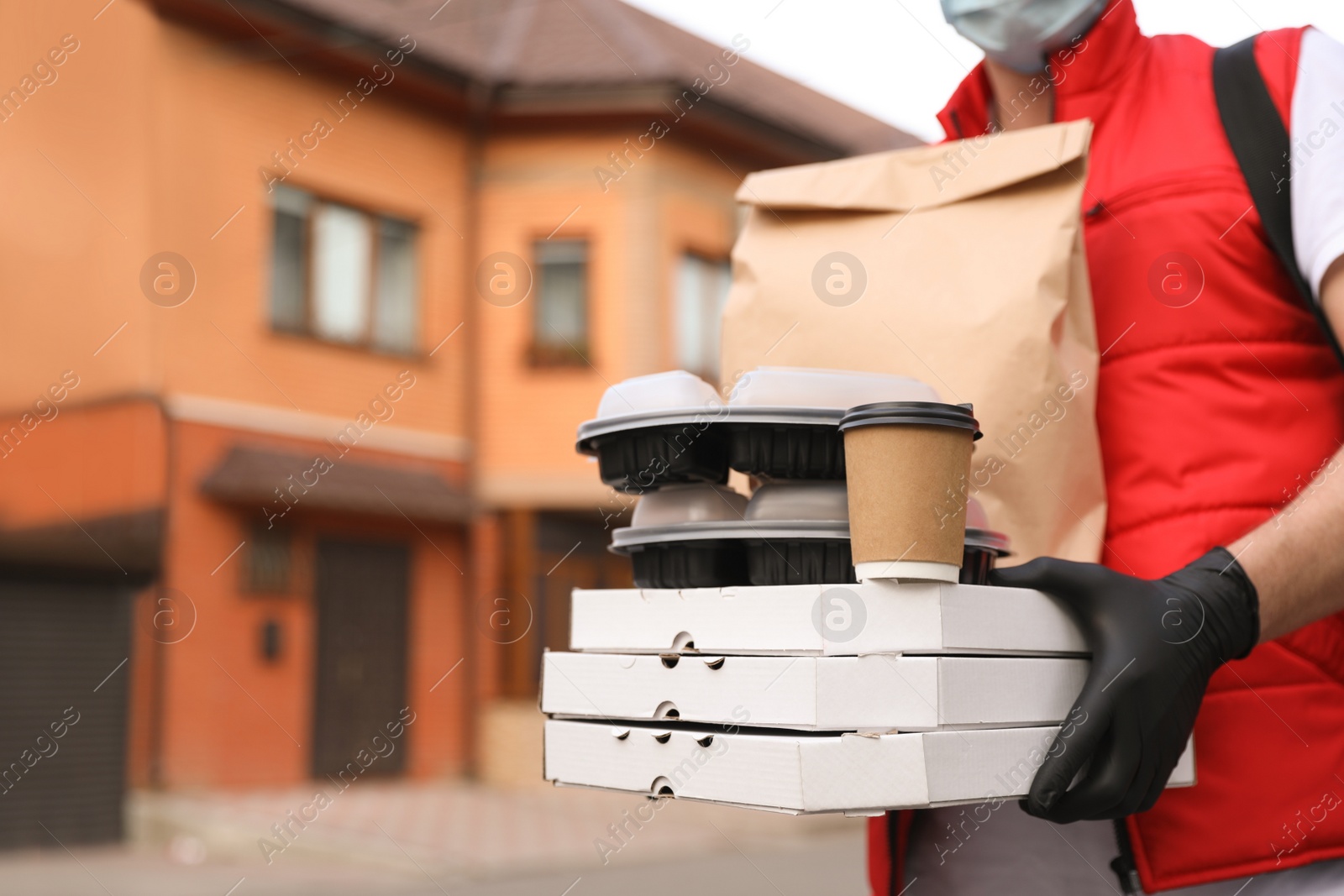 Photo of Courier in protective gloves with orders outdoors, closeup. Delivery service during coronavirus quarantine