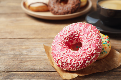 Photo of Delicious glazed donuts on wooden table, closeup. Space for text