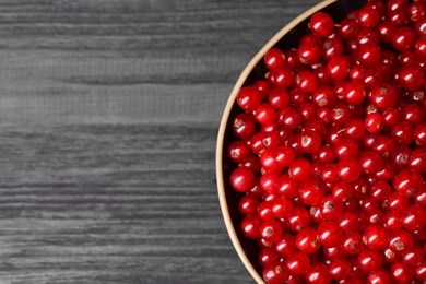 Photo of Ripe red currants in bowl on wooden rustic table, top view. Space for text