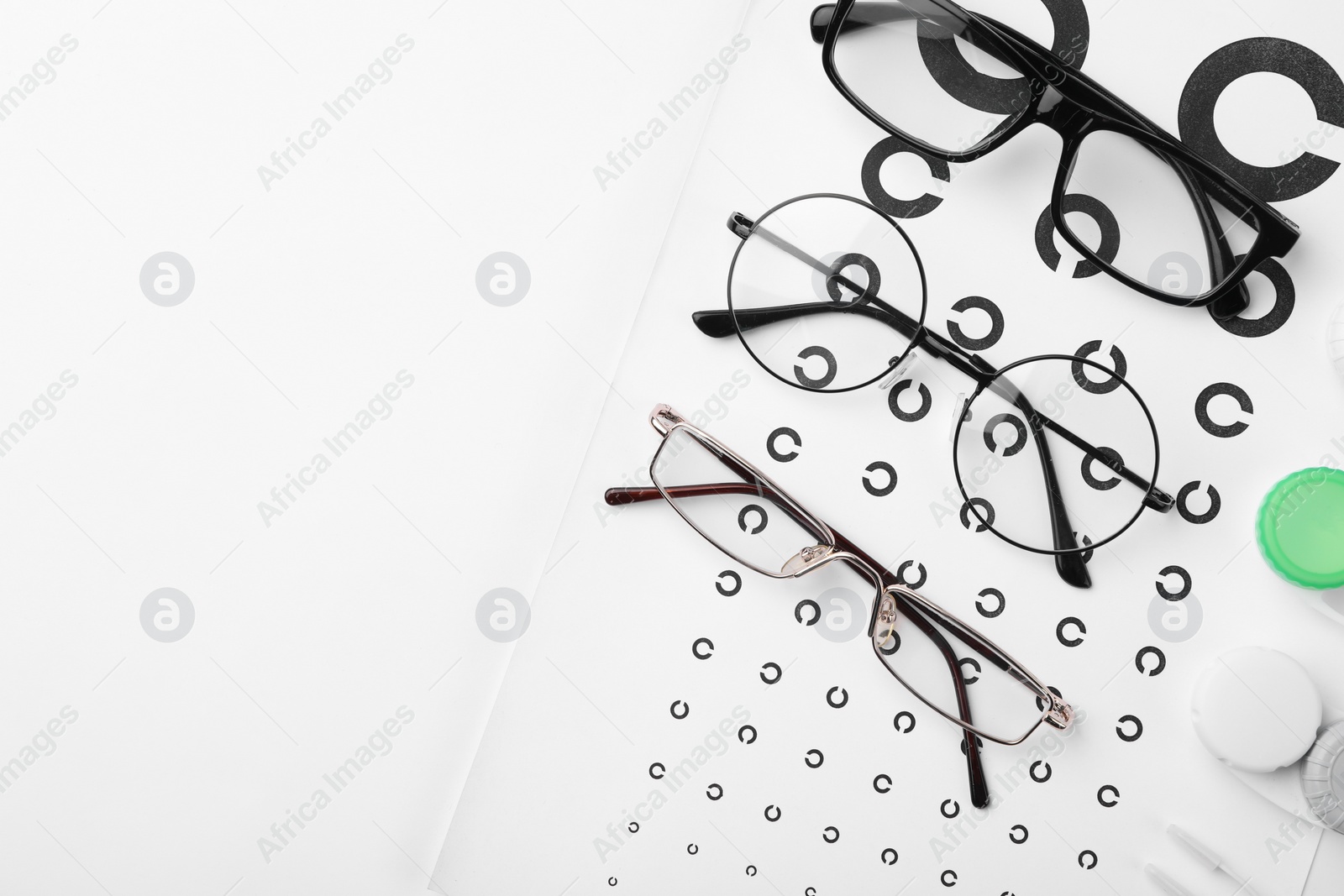 Photo of Vision test chart, glasses and lenses on white background, flat lay. Space for text